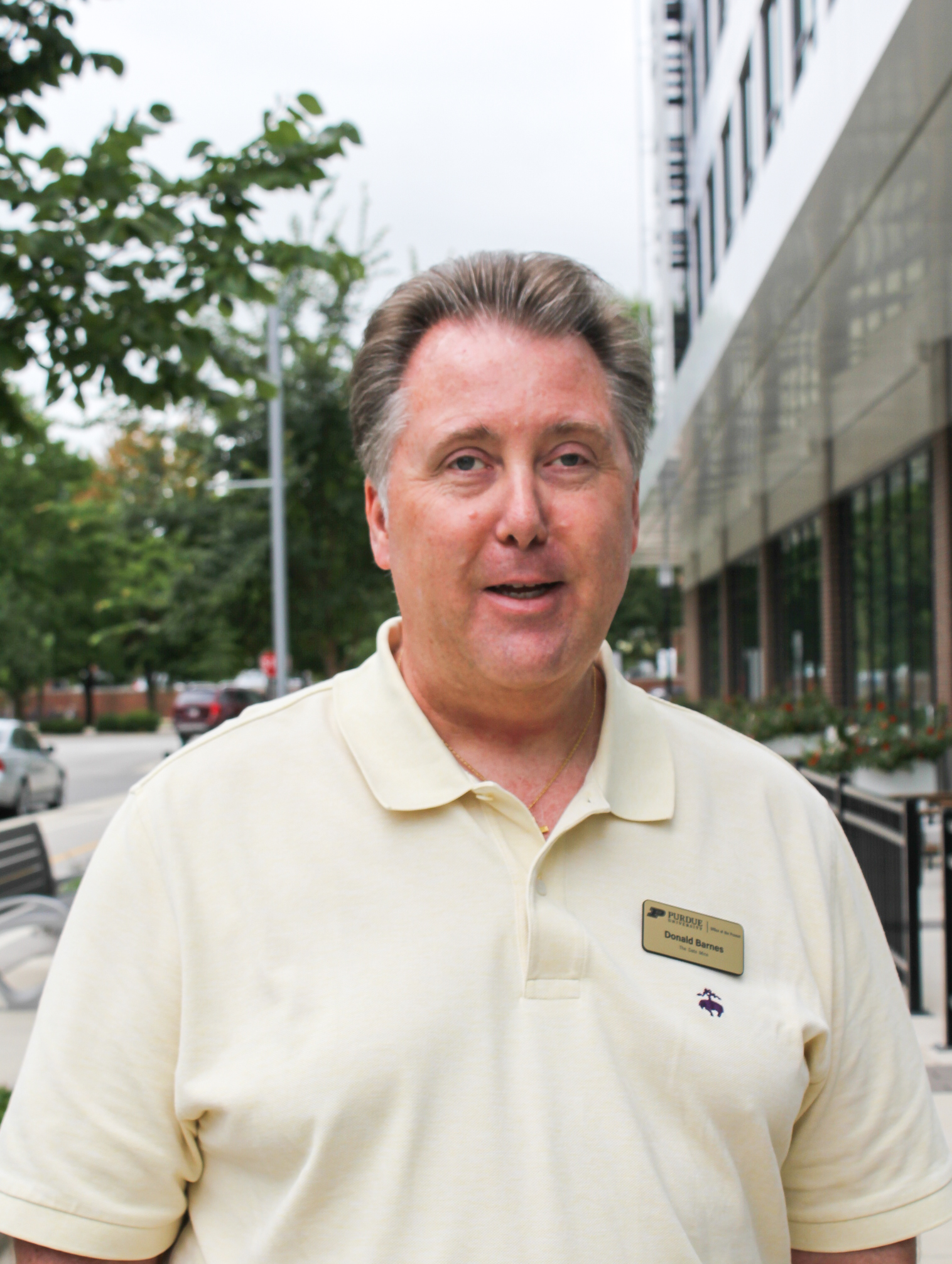 Older gentleman with pale white polo with windswept gray hair.