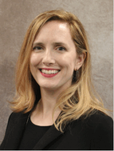 Sarah Bryant smiling at camera in headshot. Blonde hair and wearing a black shirt.