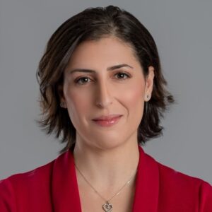 head shot of a women with dark medium length hair in a red blazer with a heart necklace