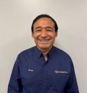 Picture of a man with dark hair in a Subaru shirt that is navy