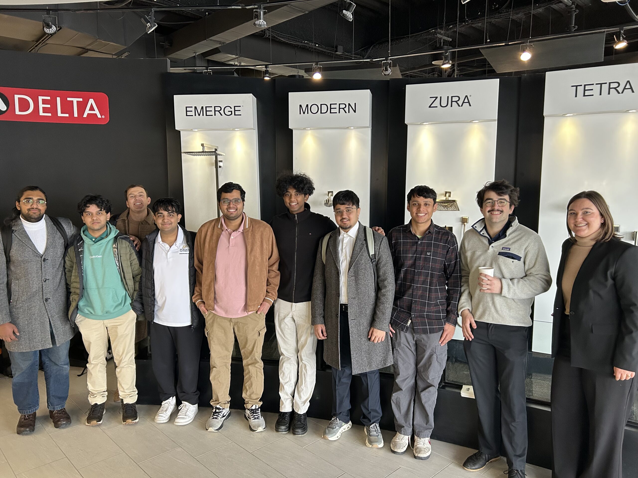 Students stand next to a series of water faucets.